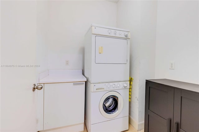 laundry room featuring cabinets and stacked washer / drying machine