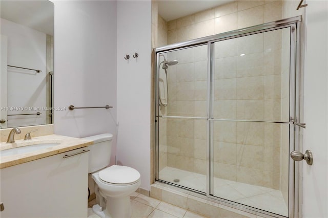 bathroom featuring tile patterned flooring, vanity, toilet, and a shower with shower door