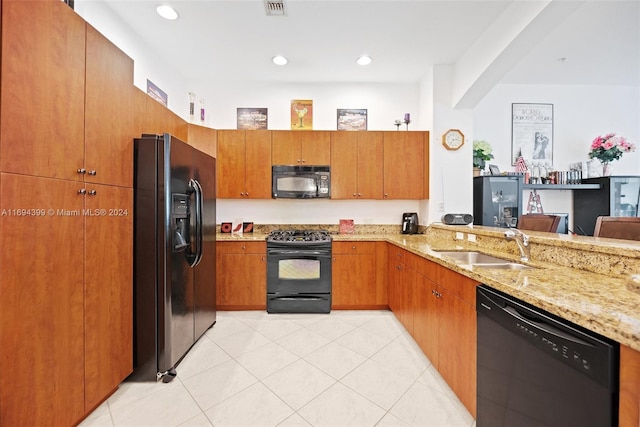 kitchen featuring kitchen peninsula, sink, light stone counters, and black appliances