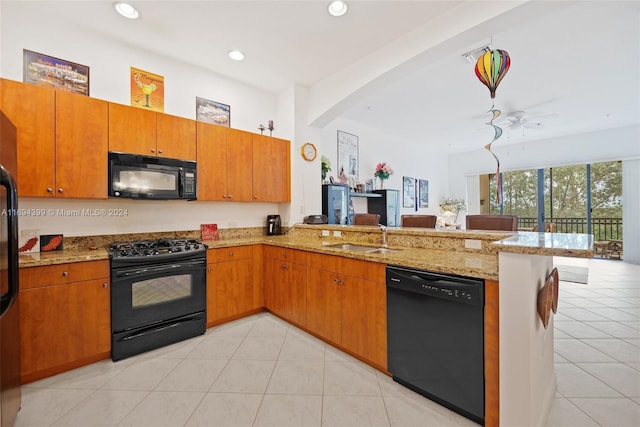 kitchen with black appliances, light stone counters, kitchen peninsula, and sink