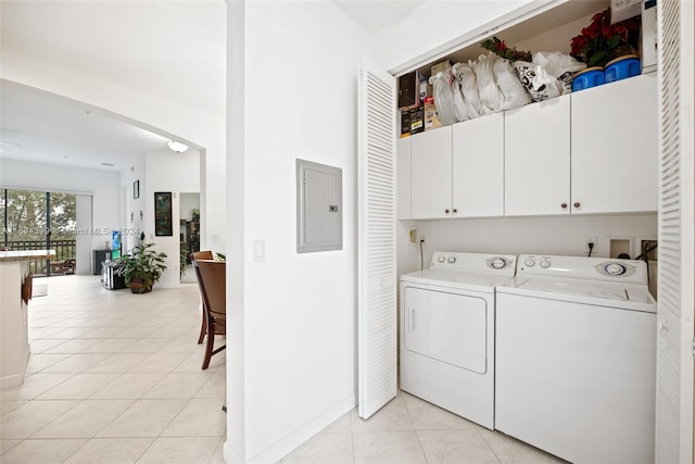 clothes washing area with washer and clothes dryer, light tile patterned flooring, cabinets, and electric panel