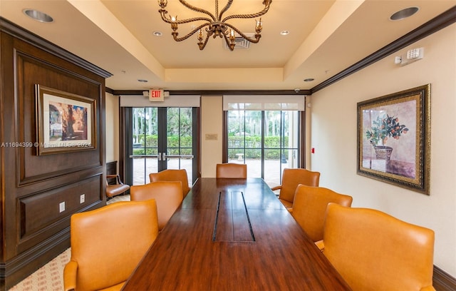 dining space with french doors, a tray ceiling, an inviting chandelier, and hardwood / wood-style floors