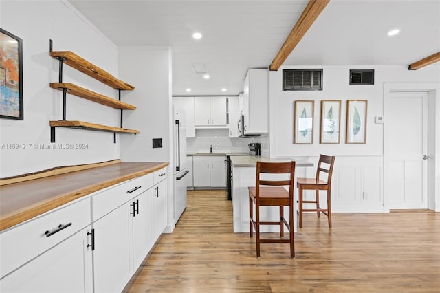 kitchen with butcher block counters, white cabinetry, white fridge, and light wood-type flooring