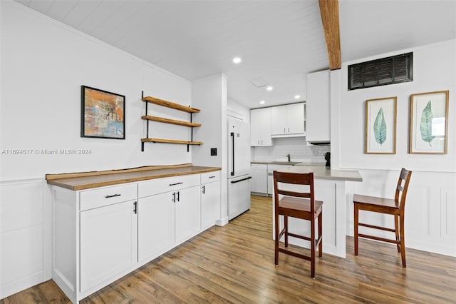 kitchen with a kitchen breakfast bar, white cabinets, white appliances, and light wood-type flooring