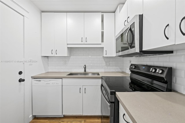 kitchen featuring black range with electric stovetop, white cabinetry, dishwasher, sink, and light hardwood / wood-style flooring