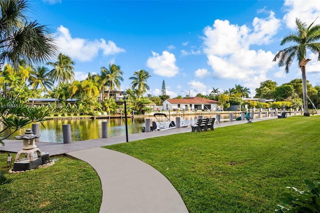 view of property's community with a yard, a water view, and a boat dock