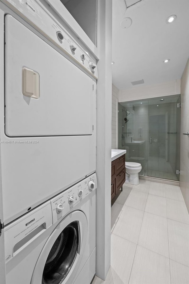 laundry room featuring stacked washer and dryer and light tile patterned flooring