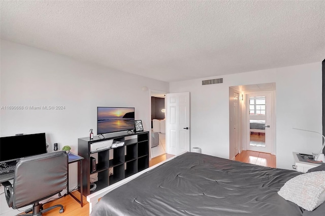 bedroom with a textured ceiling and hardwood / wood-style flooring