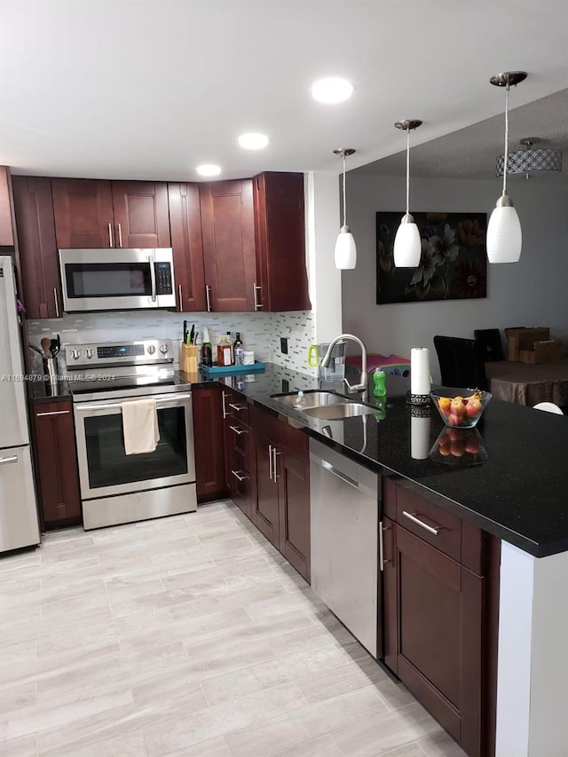 kitchen featuring sink, hanging light fixtures, stainless steel appliances, backsplash, and kitchen peninsula