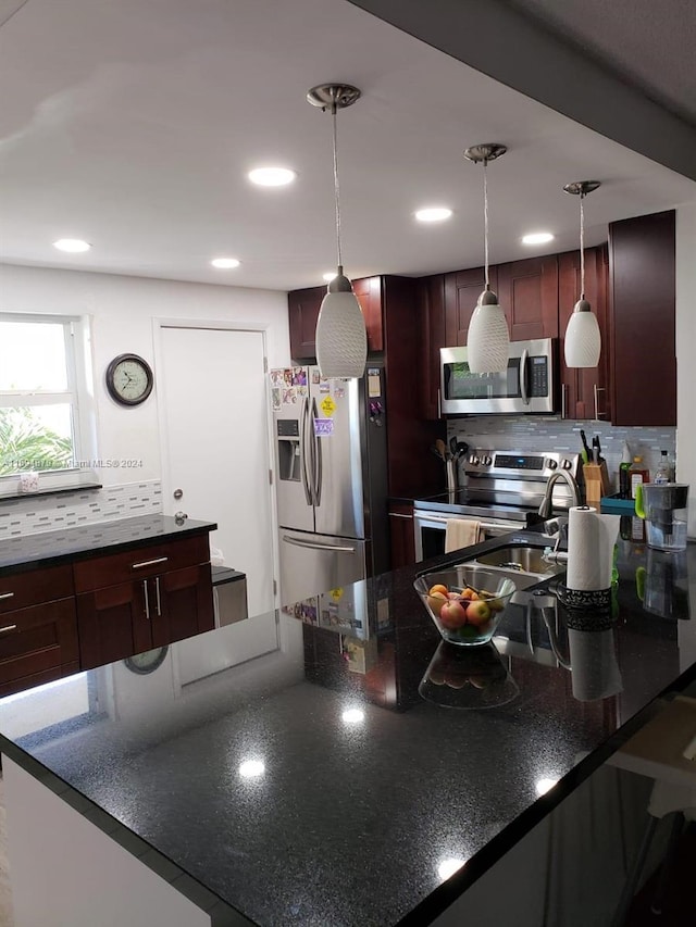 kitchen with backsplash, decorative light fixtures, and stainless steel appliances