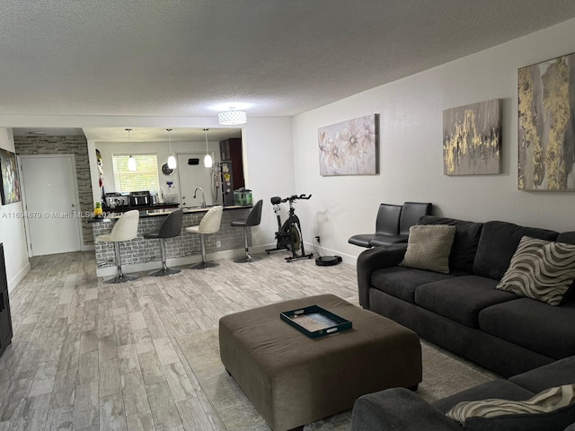 living room featuring sink, light hardwood / wood-style floors, and a textured ceiling