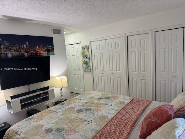 bedroom with a textured ceiling and two closets