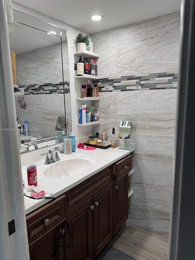 bathroom with hardwood / wood-style floors, vanity, and tile walls