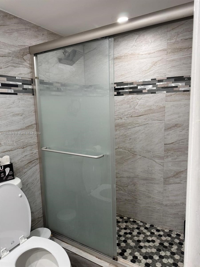 bathroom featuring a shower with door and toilet