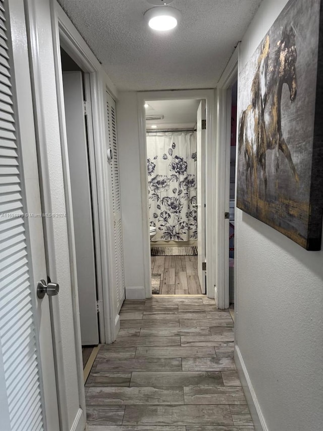 hallway with hardwood / wood-style floors and a textured ceiling