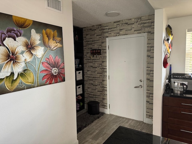 foyer entrance with wood-type flooring and a textured ceiling