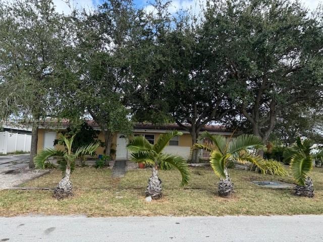 view of property hidden behind natural elements featuring a front yard