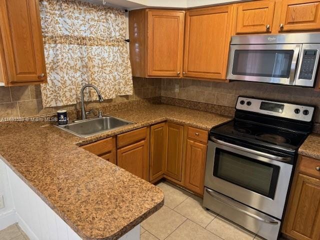 kitchen featuring decorative backsplash, appliances with stainless steel finishes, kitchen peninsula, sink, and light tile patterned floors