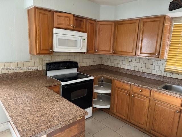 kitchen featuring decorative backsplash, light tile patterned floors, and white appliances