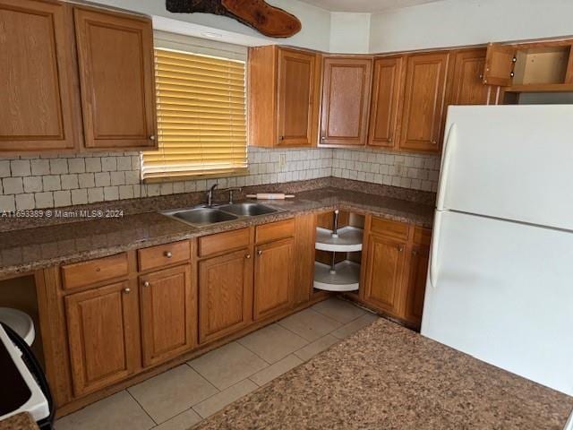 kitchen featuring light tile patterned floors, white refrigerator, backsplash, and sink