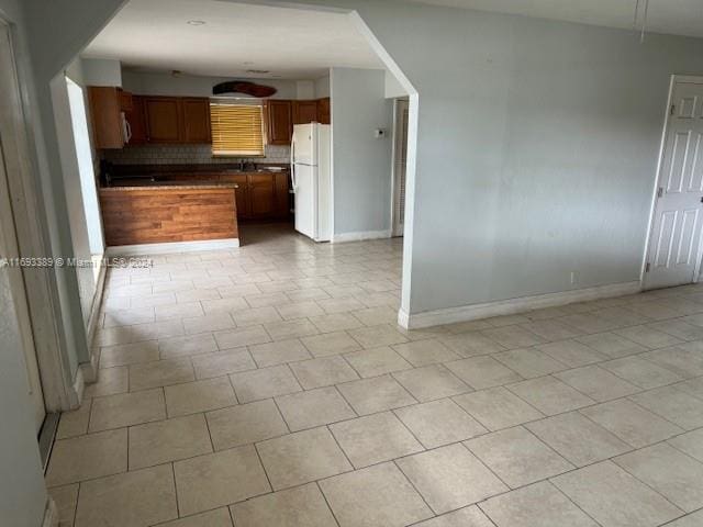 kitchen featuring white fridge, light tile patterned floors, and tasteful backsplash