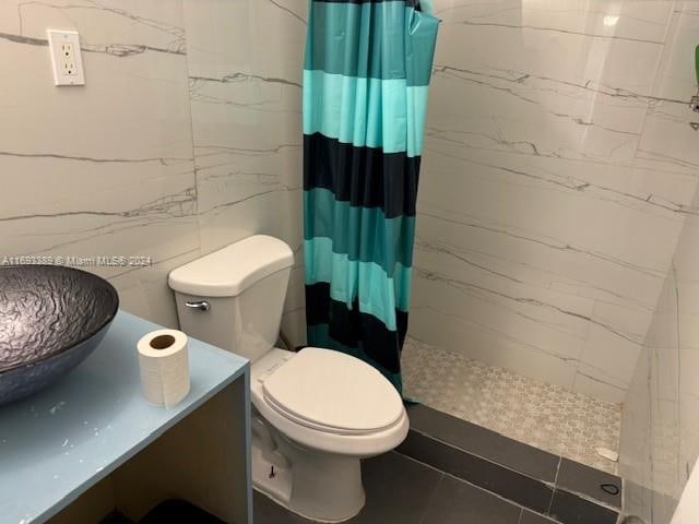 bathroom featuring a shower with shower curtain, toilet, and sink