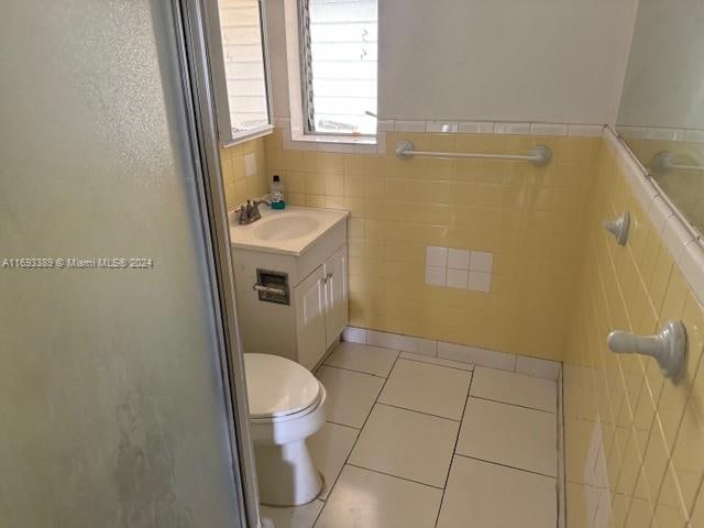 bathroom with tile patterned flooring, vanity, toilet, and tile walls