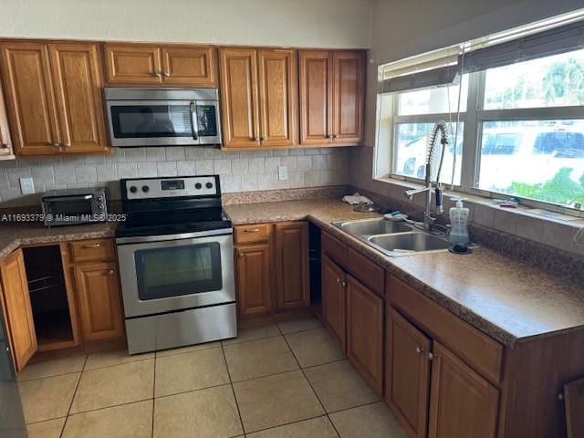 kitchen featuring a sink, appliances with stainless steel finishes, and brown cabinets