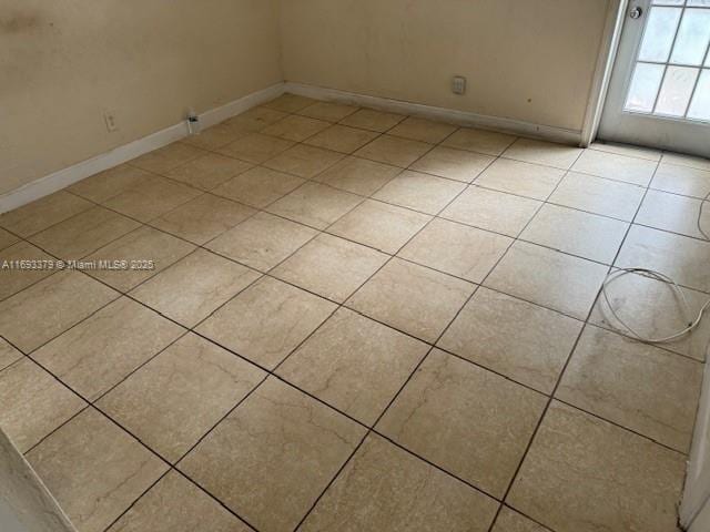 unfurnished room featuring baseboards and light tile patterned flooring