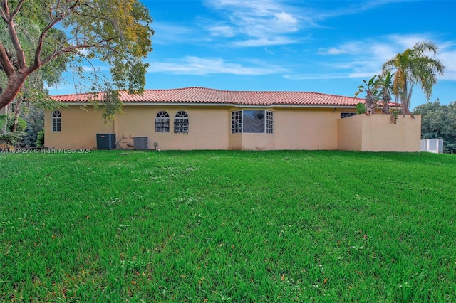 back of house featuring central AC unit and a lawn