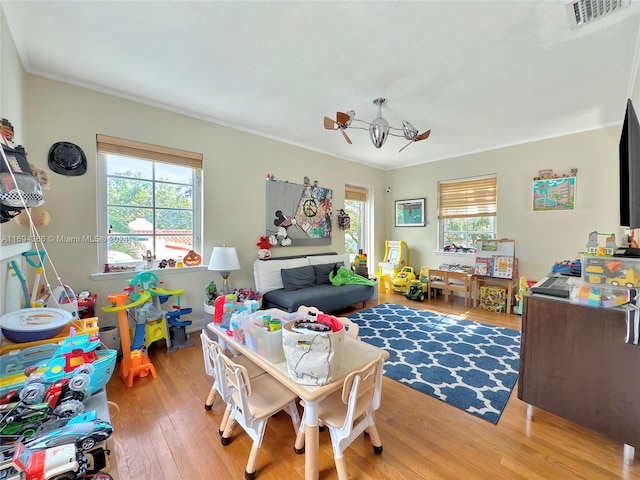 recreation room featuring plenty of natural light, light hardwood / wood-style floors, and ornamental molding