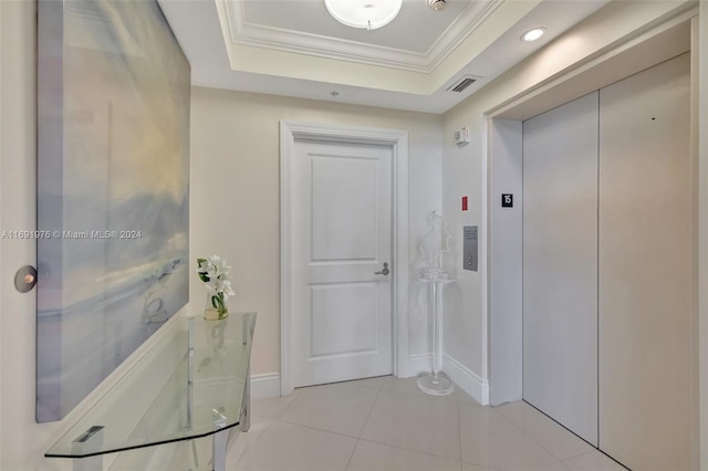 hall featuring a tray ceiling, elevator, crown molding, and light tile patterned flooring