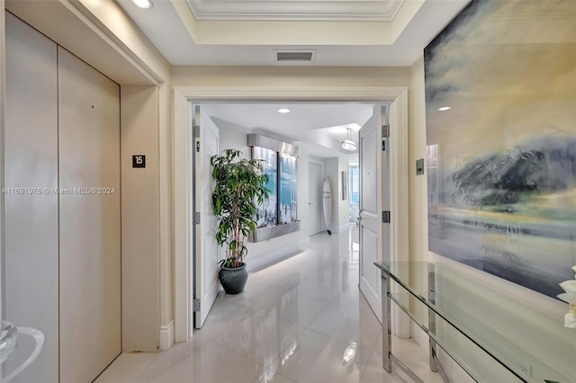 hallway featuring a tray ceiling, elevator, and ornamental molding