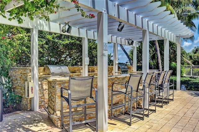 view of patio featuring a pergola, area for grilling, exterior bar, and an outdoor kitchen