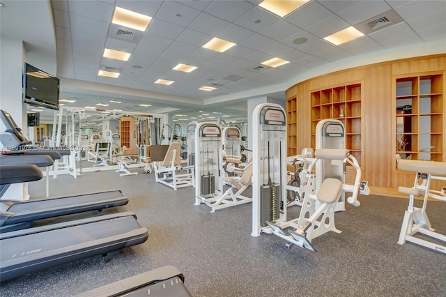 workout area with a paneled ceiling and wooden walls