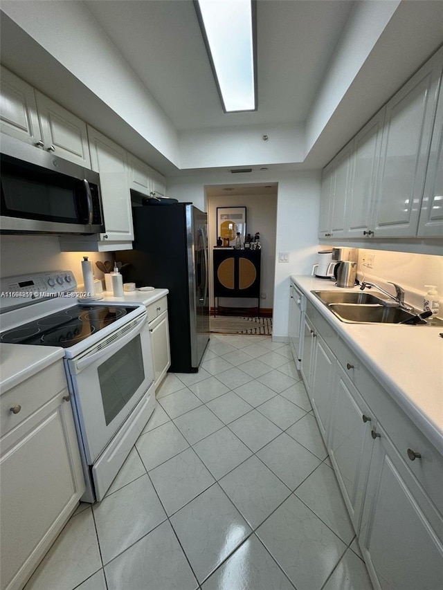 kitchen with light tile patterned floors, white cabinetry, white electric stove, and sink