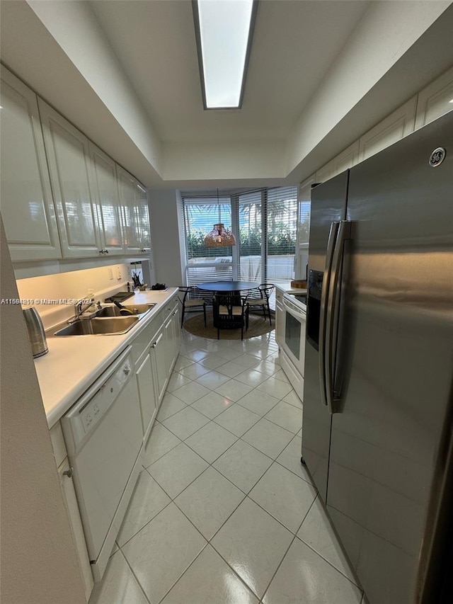 kitchen with white cabinets, white appliances, sink, and light tile patterned floors