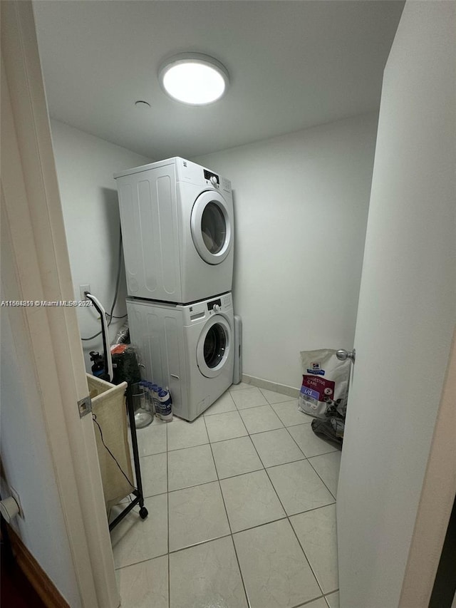 laundry area with stacked washing maching and dryer and light tile patterned flooring