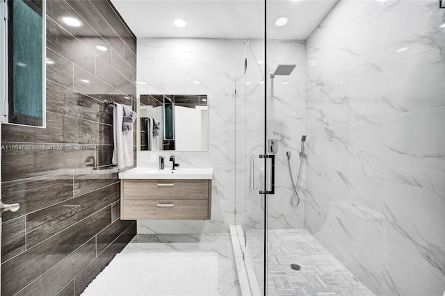 bathroom with a shower with door, vanity, and tile walls