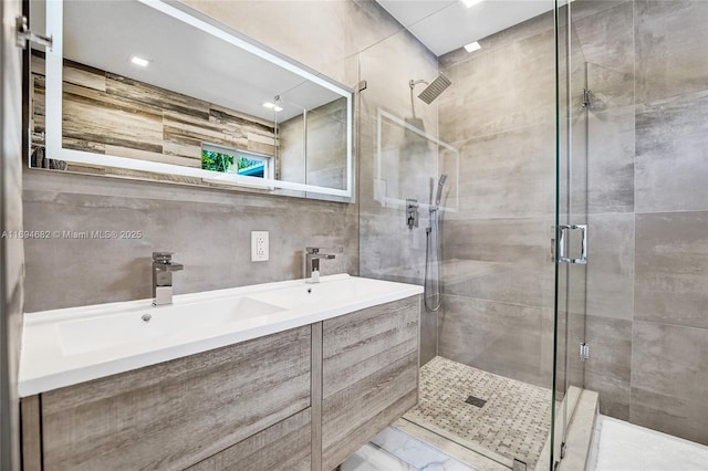 bathroom with walk in shower, vanity, and tile walls