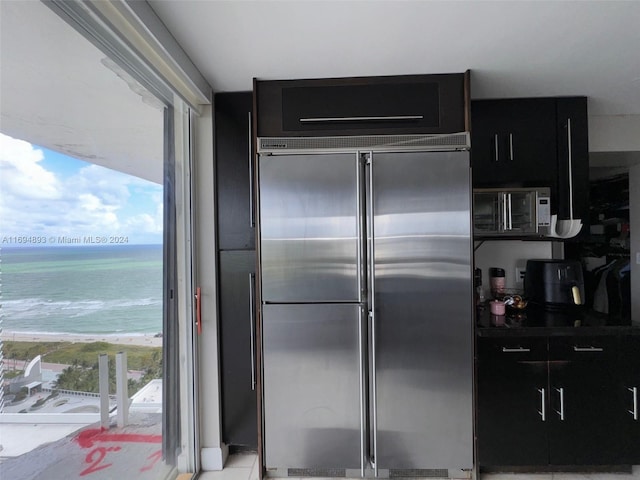 kitchen featuring a water view, a healthy amount of sunlight, a beach view, and appliances with stainless steel finishes