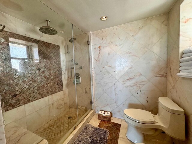 bathroom featuring tile patterned flooring, a shower with door, tile walls, and toilet