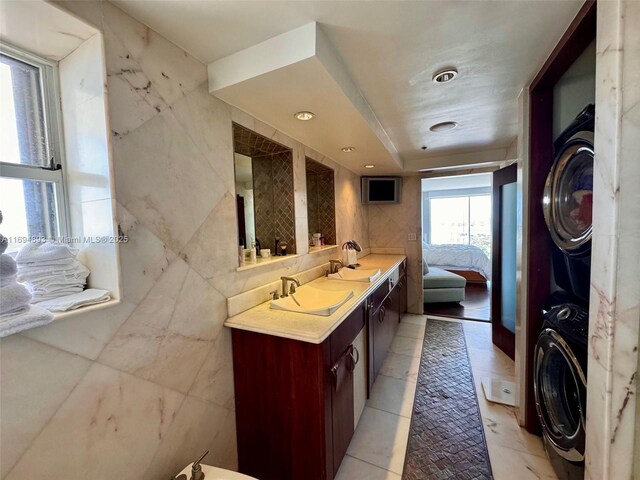 bathroom with vanity, a bidet, tile patterned flooring, tile walls, and stacked washer / drying machine