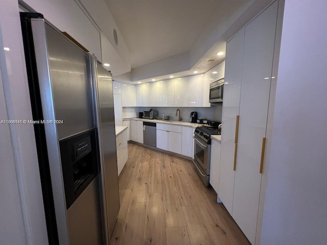 kitchen with light wood-type flooring, white cabinetry, sink, and appliances with stainless steel finishes