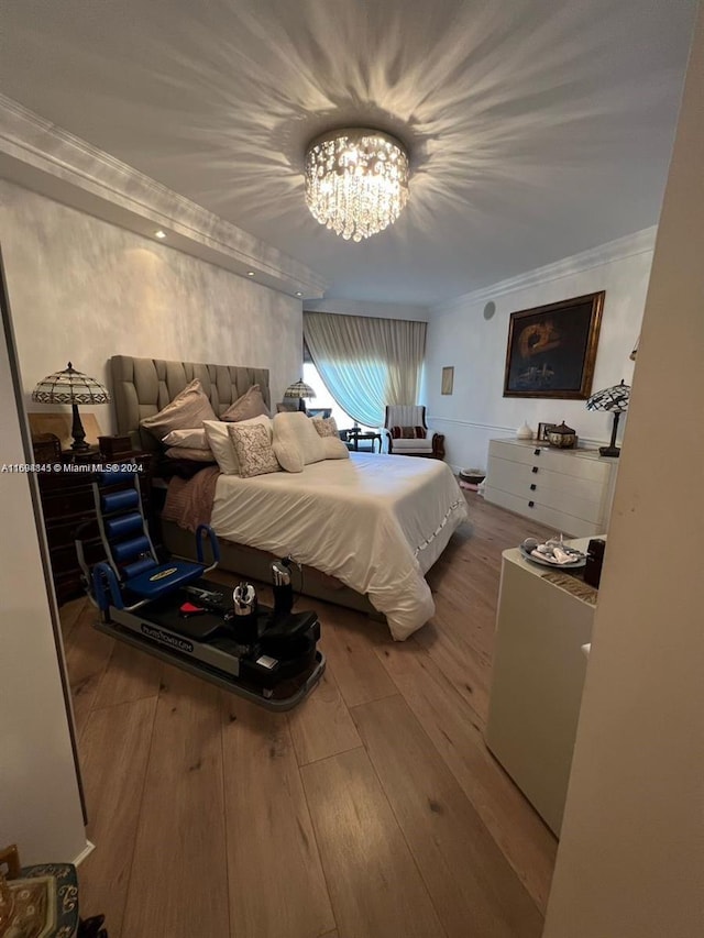 bedroom with hardwood / wood-style flooring, ornamental molding, and a chandelier