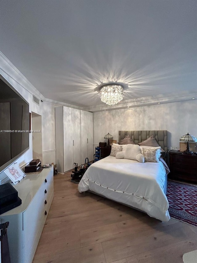 bedroom featuring light hardwood / wood-style flooring, a chandelier, and ornamental molding