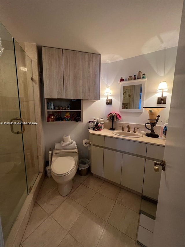 bathroom with tile patterned floors, vanity, a shower with shower door, and toilet