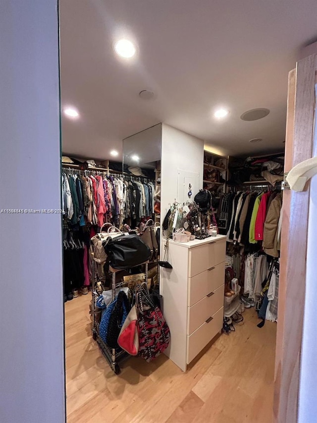 walk in closet with light hardwood / wood-style flooring