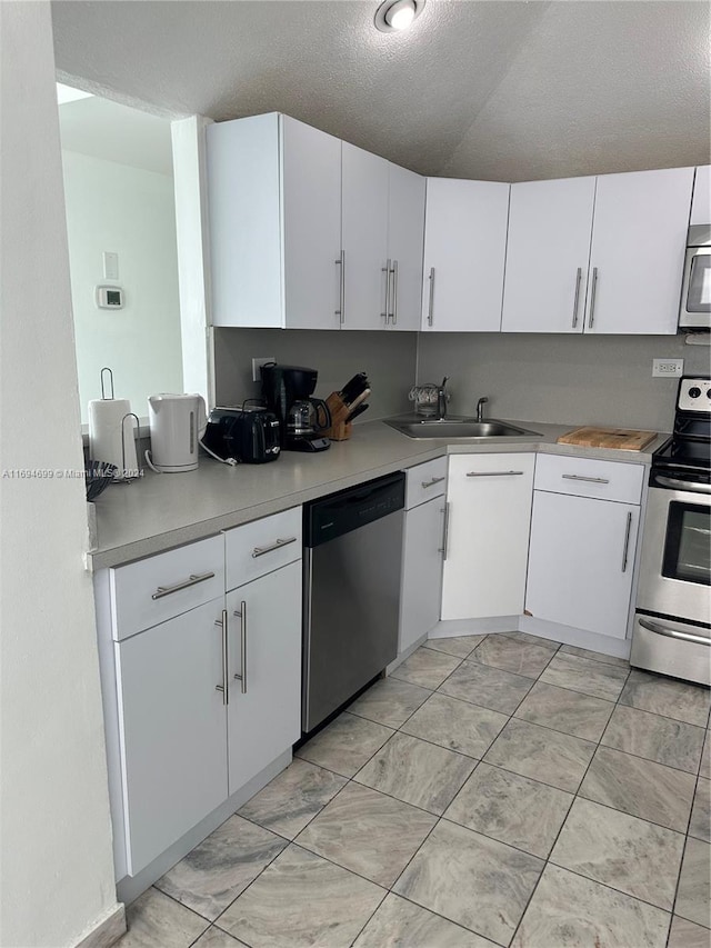 kitchen featuring white cabinets, appliances with stainless steel finishes, a textured ceiling, and sink