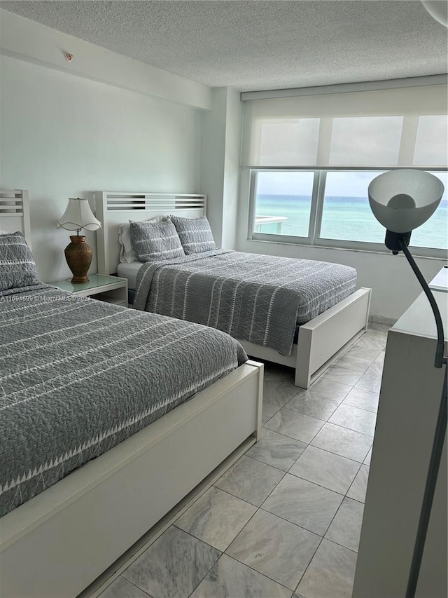 bedroom with a textured ceiling and a water view